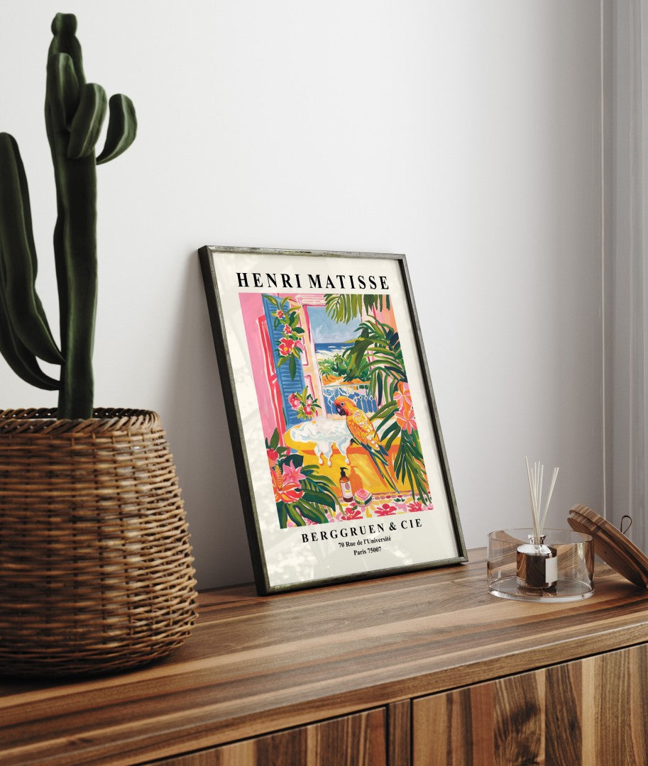 Framed Matisse inspired print with a parrot by a yellow bathtub, tropical foliage, and ocean backdrop for bathroom.