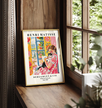 Framed wall art of a woman in a floral dress embracing her cat.