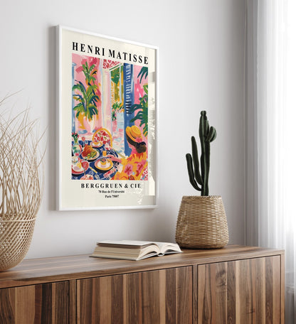 Framed print of Mediterranean dining scene with food, wine, and florals.