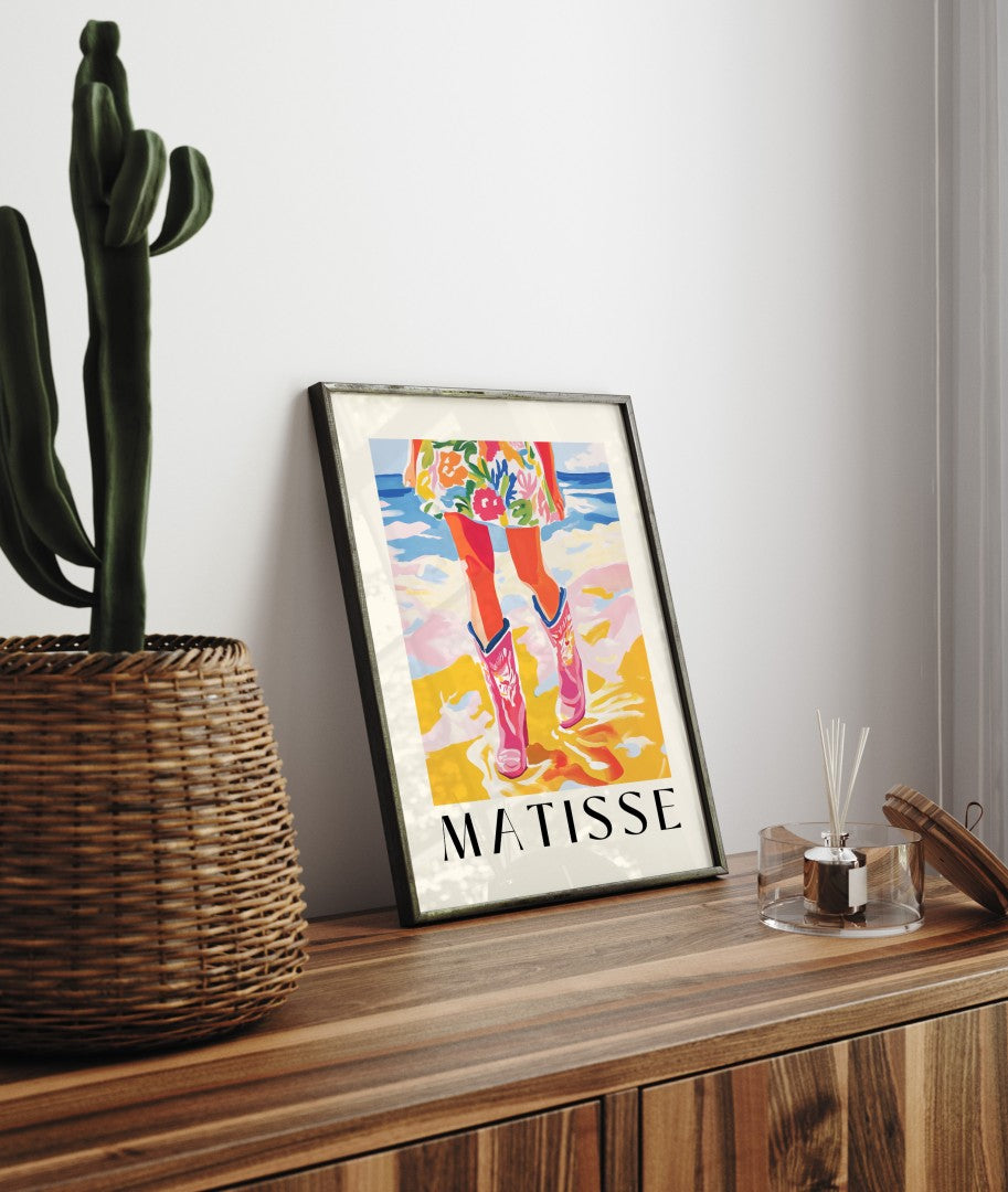 Framed art print featuring pink cowboy boots and floral dress at the ocean in bold Matisse style