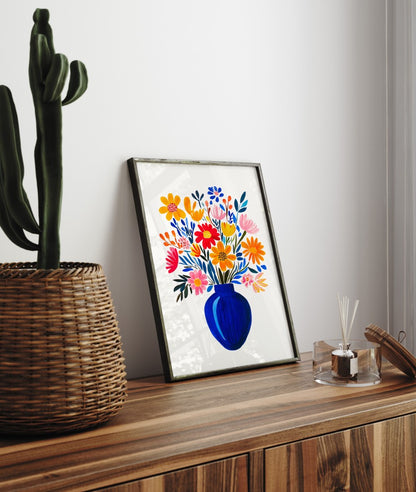 Bright floral framed art print with bold blue vase and multicolor flowers